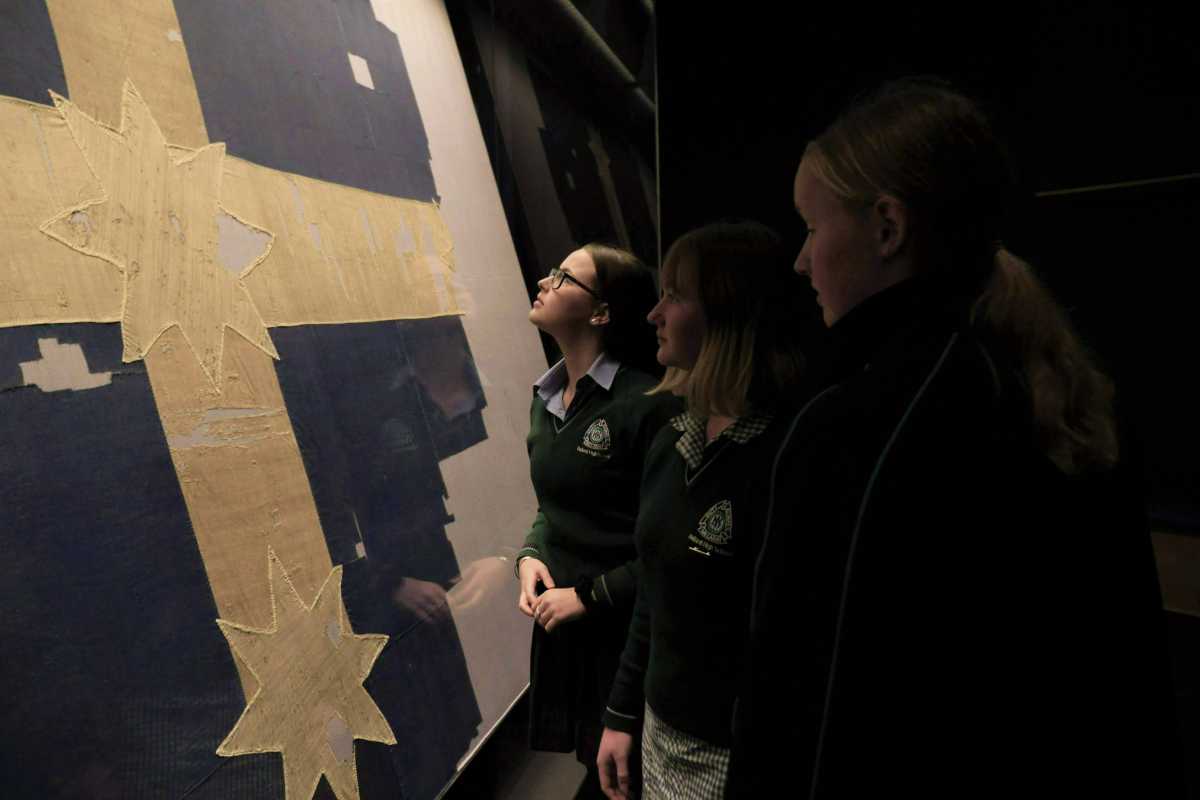 3 students look at eureka flag